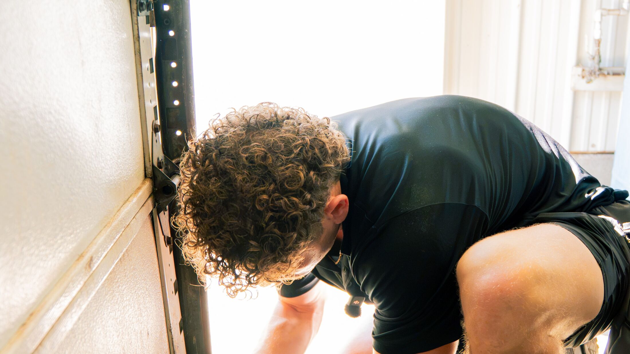 An Elevation technician working on the bottom section and bracket of a garage door