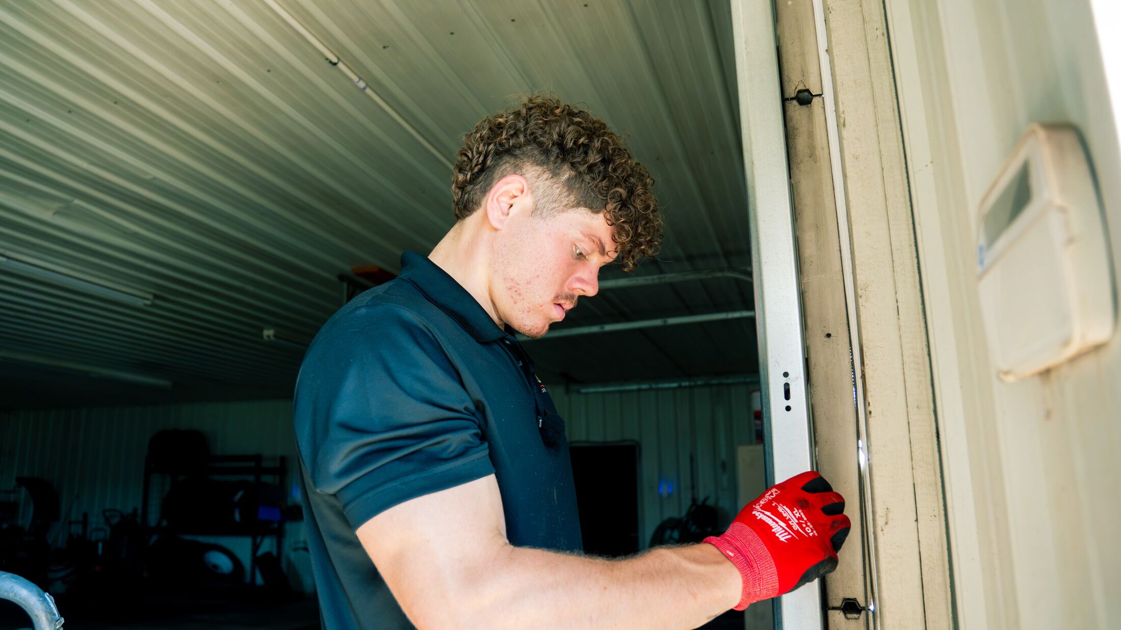 An Elevation technician checking the lock and jamb hardware on a garage door