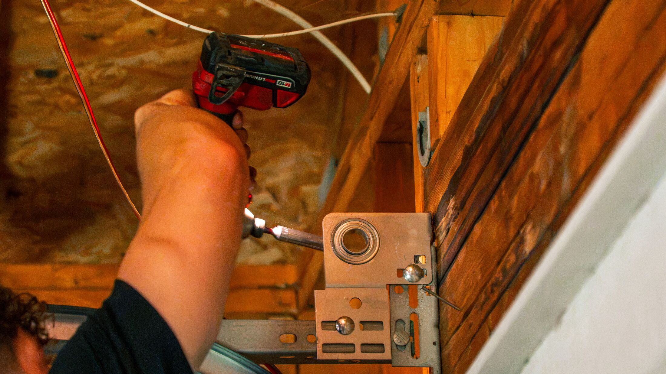 An Elevation technician working on the wiring at a garage door opener's wall bracket