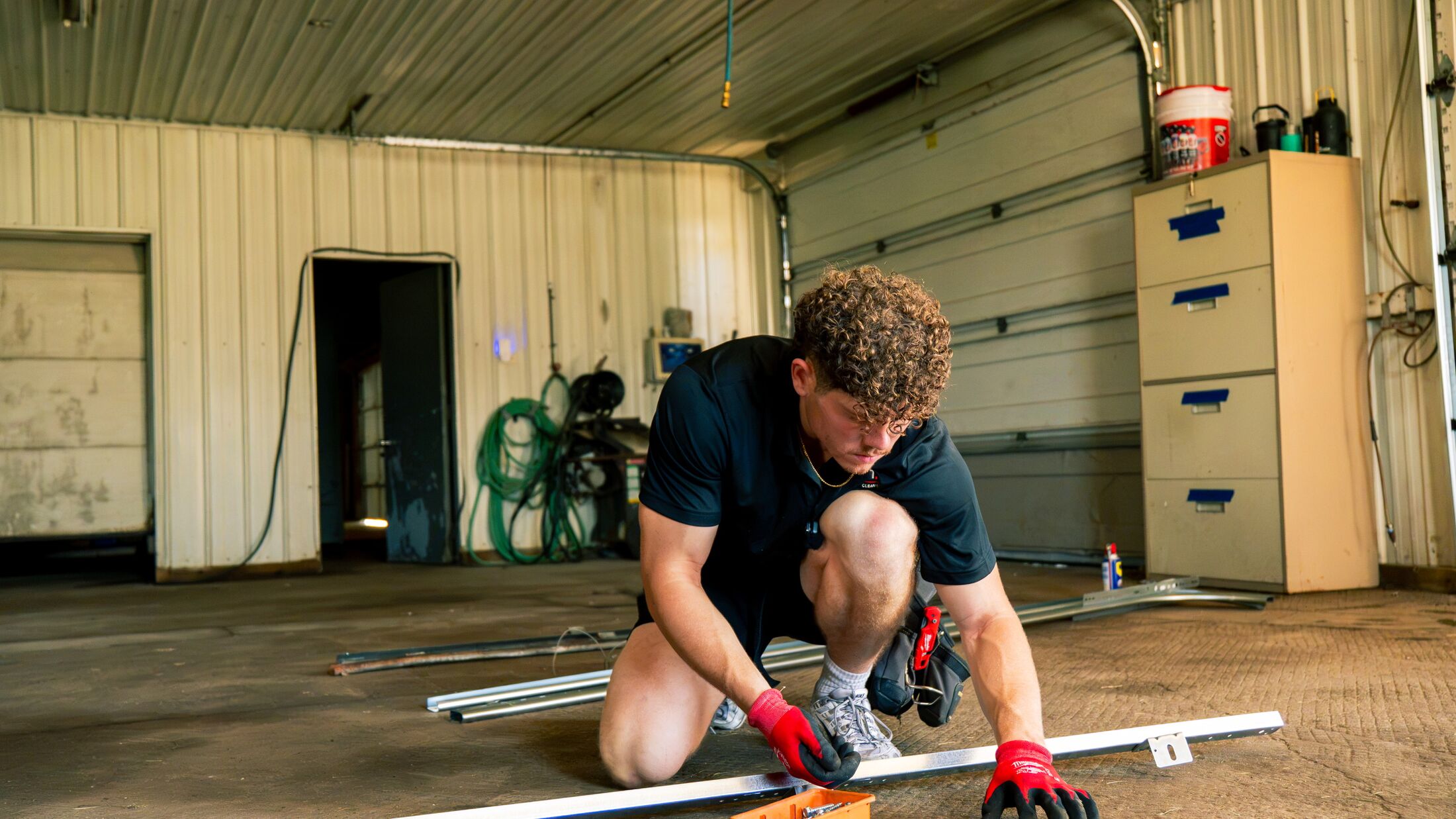 An Elevation technician assembling new garage door track on the floor of a garage